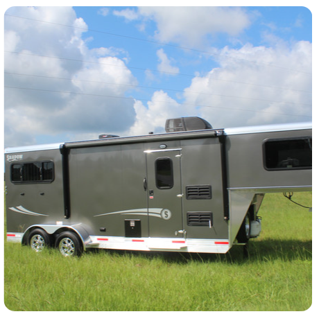 A horse trailer is parked in a grassy field