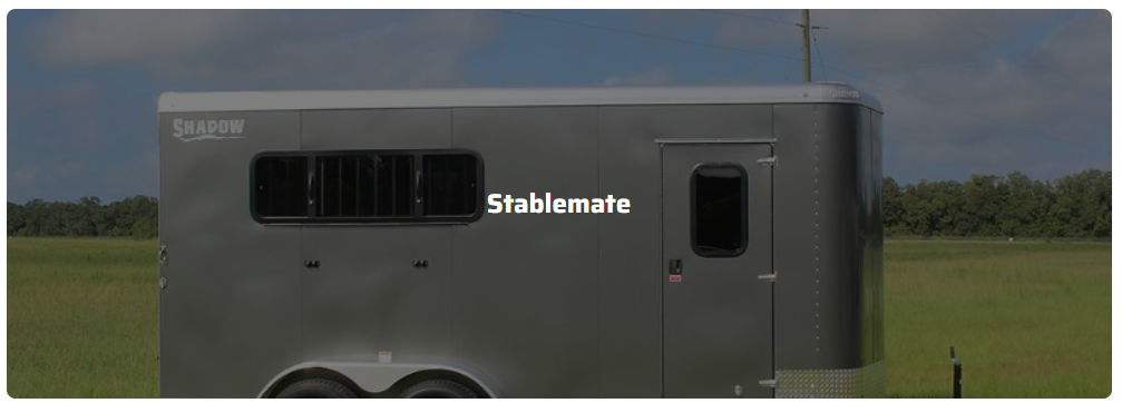 A horse trailer is parked in a grassy field.