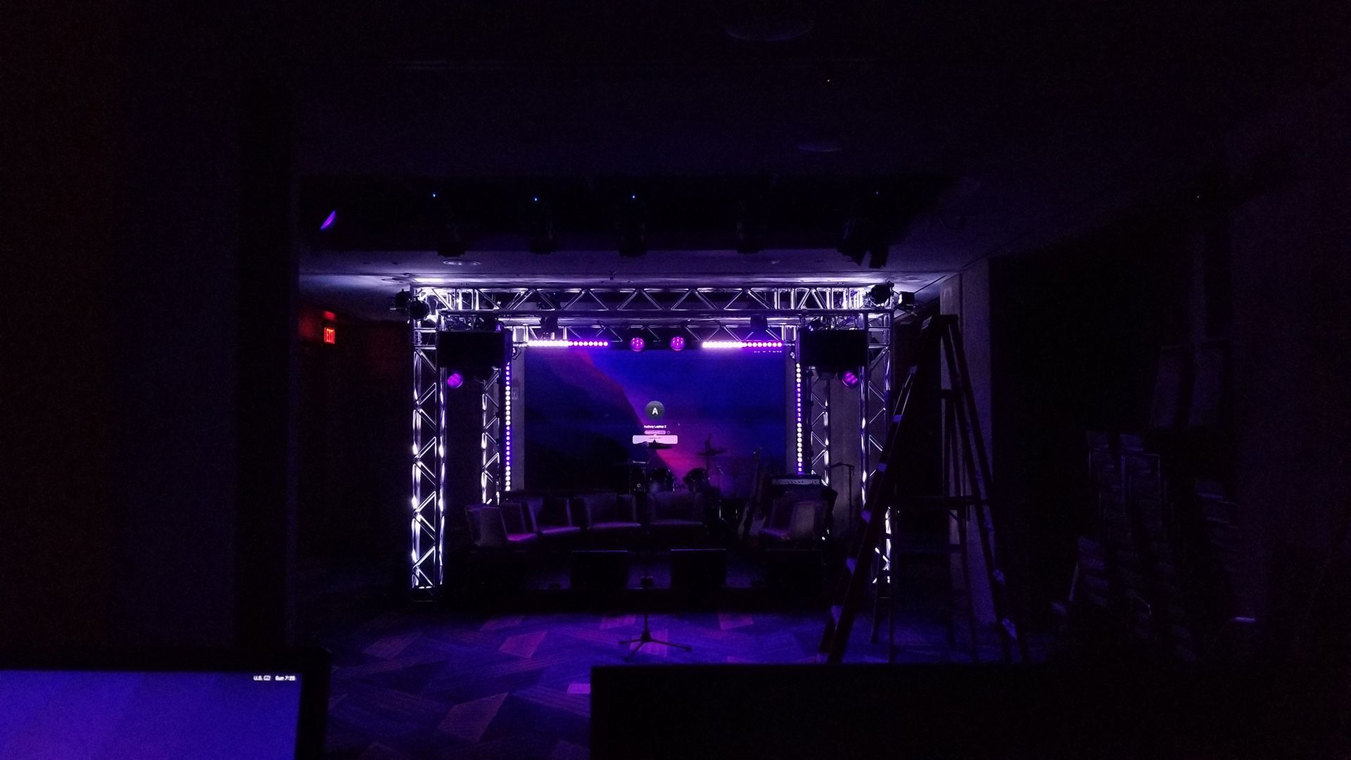 Dark room with a brightly lit stage set up with lights and equipment.