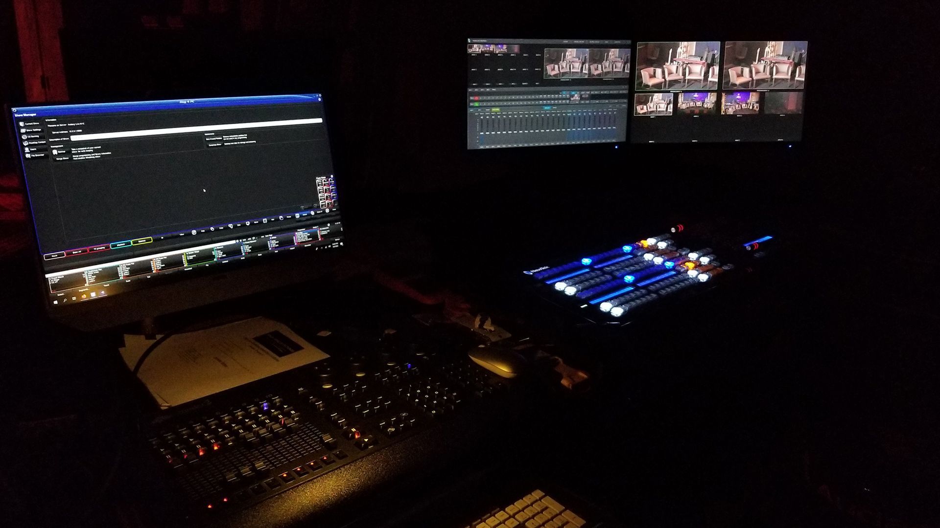 Dark room with video editing setup: monitor, keyboard, control panel, and preview screens.