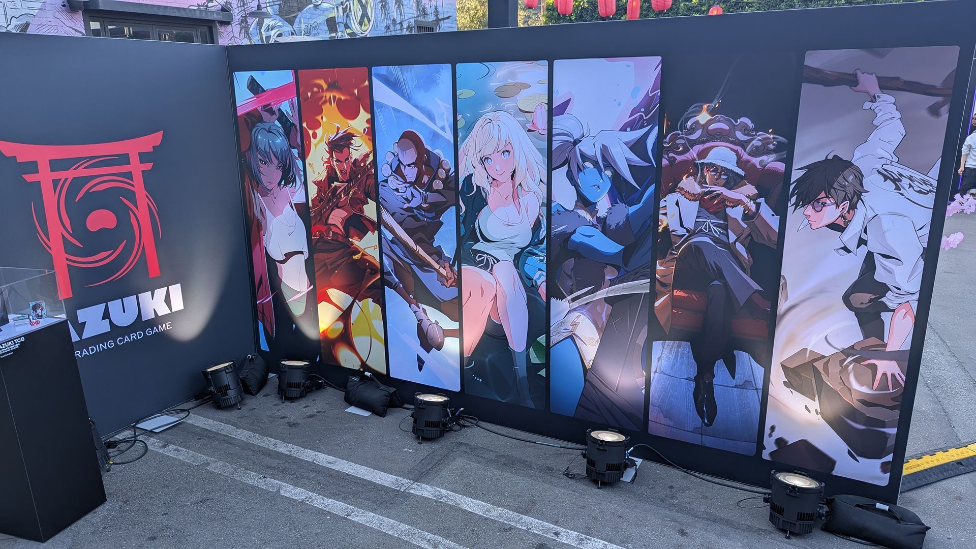Anime artwork display with stage lighting. Red, orange, and blue hues. Features several characters.