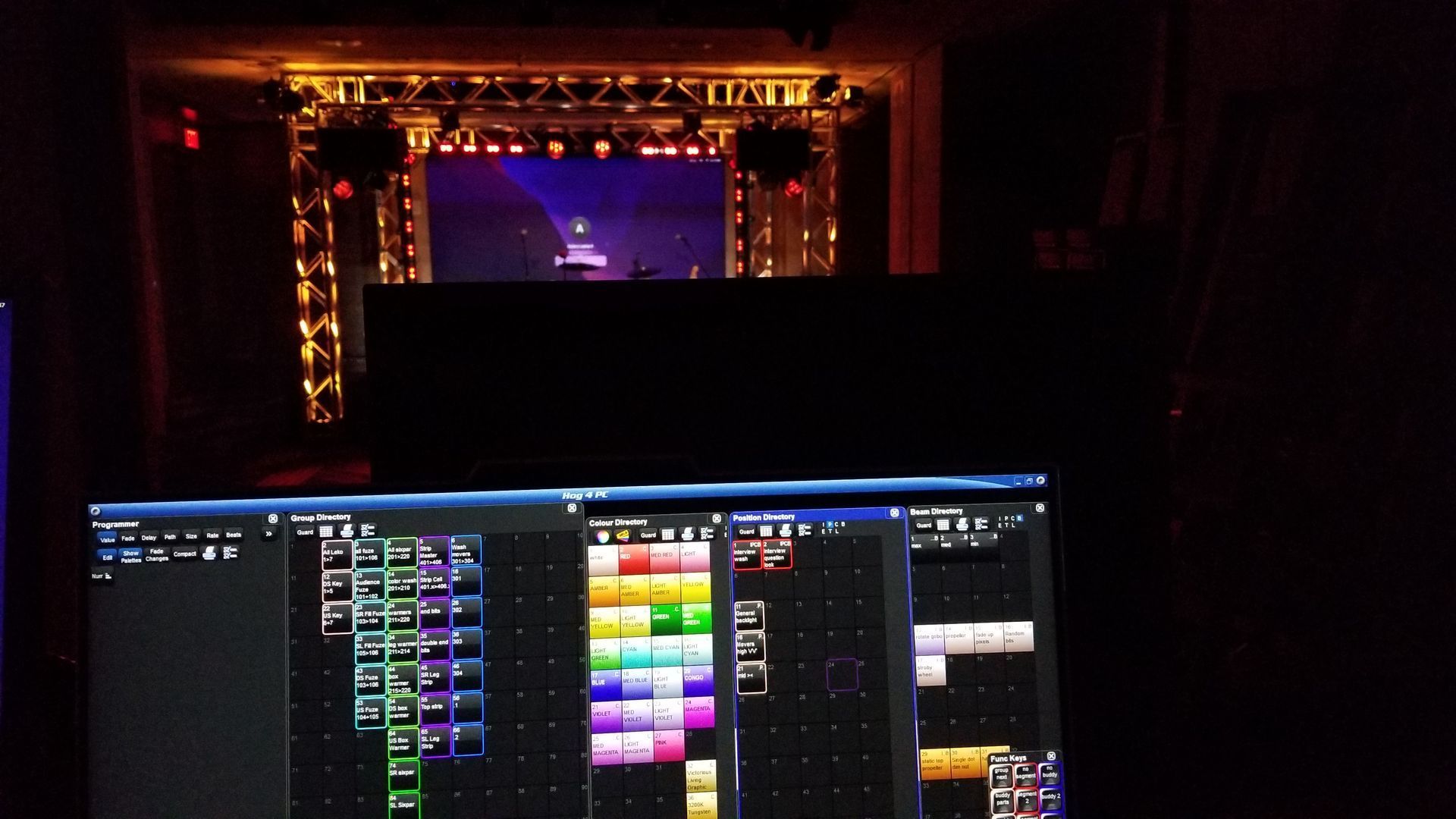 A video editing screen in a dark room with a stage lit up in the background.