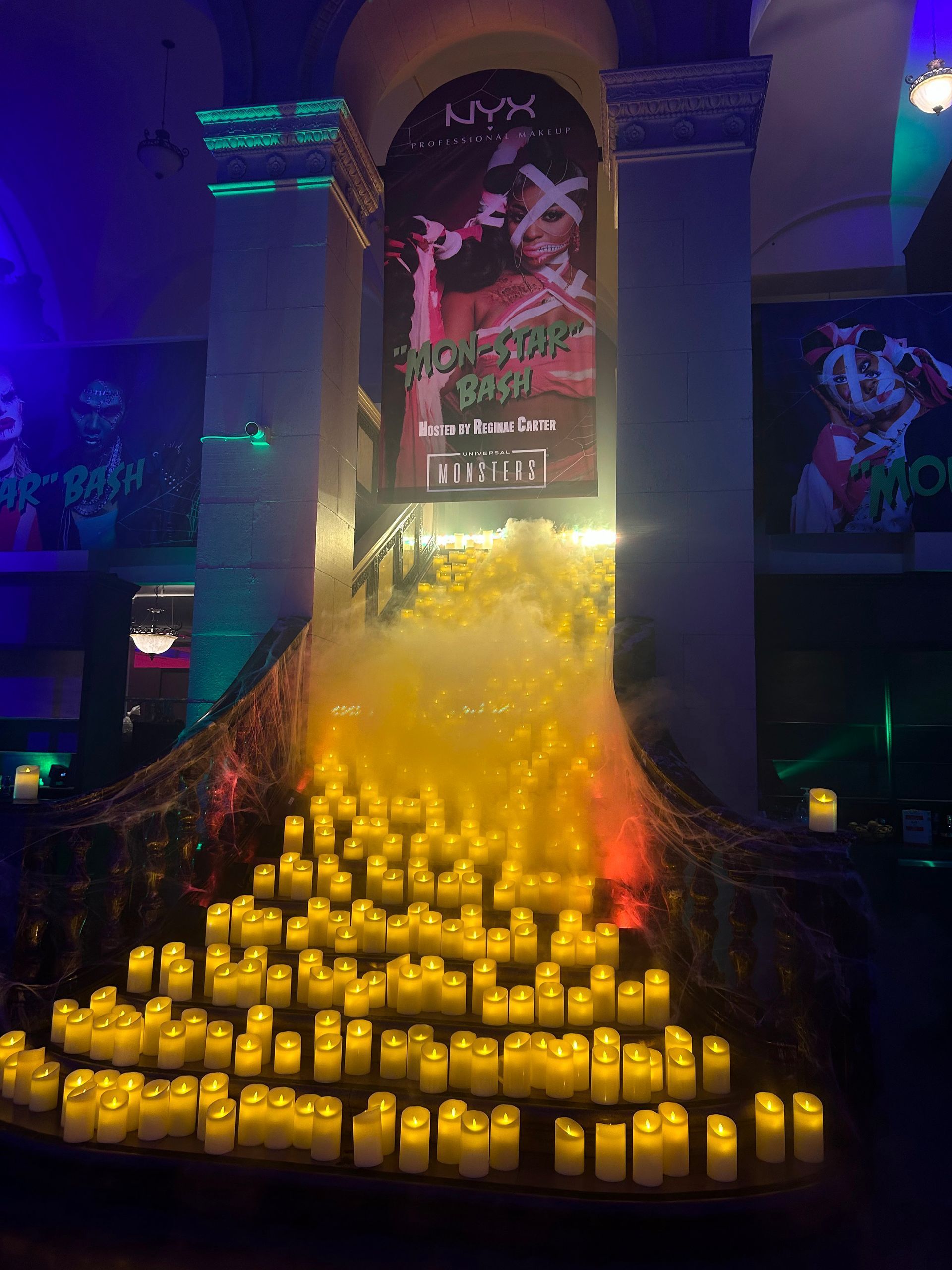 Halloween display: Stacked candles with fog, banner, and eerie decor in a dim hall.