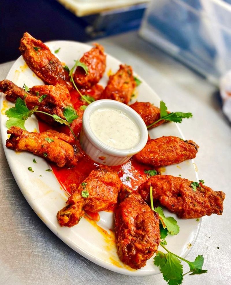 A white plate topped with chicken wings and a small bowl of ranch dressing