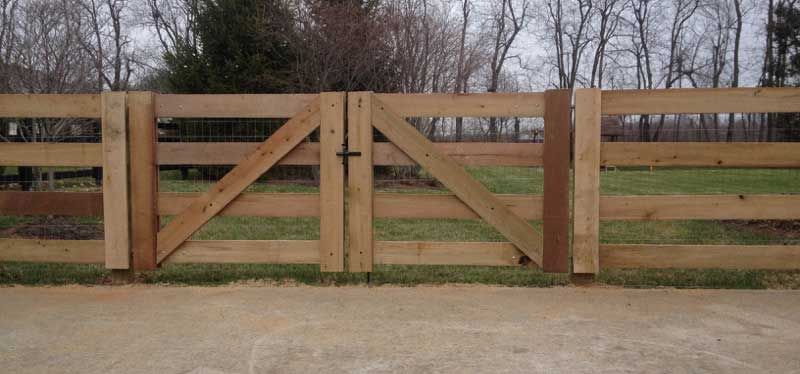 A wooden fence with a gate in the middle of a field.