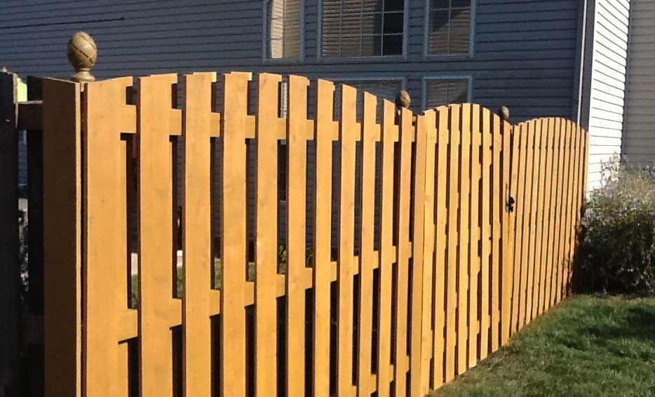 A wooden picket fence is in front of a house.
