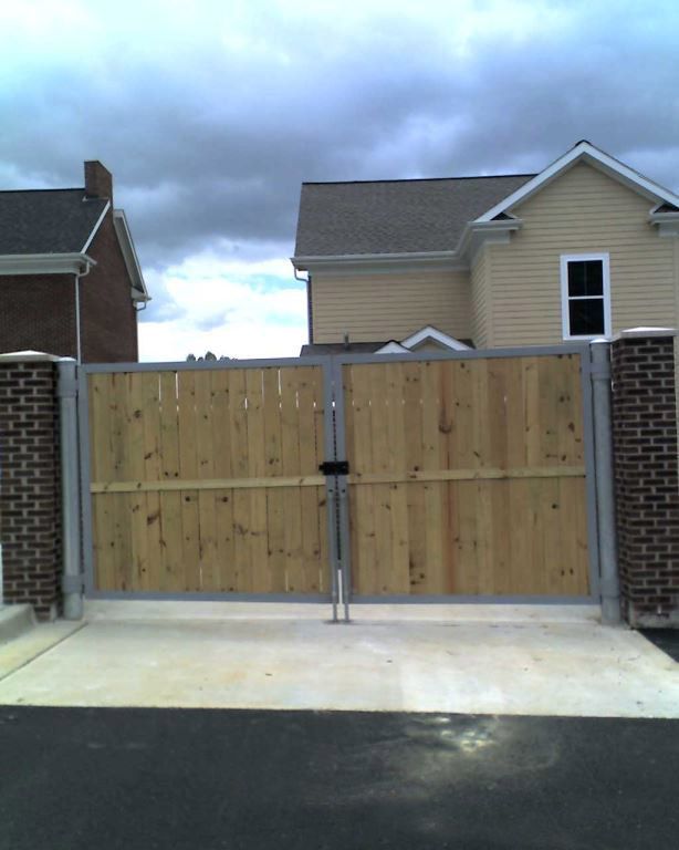 A wooden gate in front of a house on a cloudy day.
