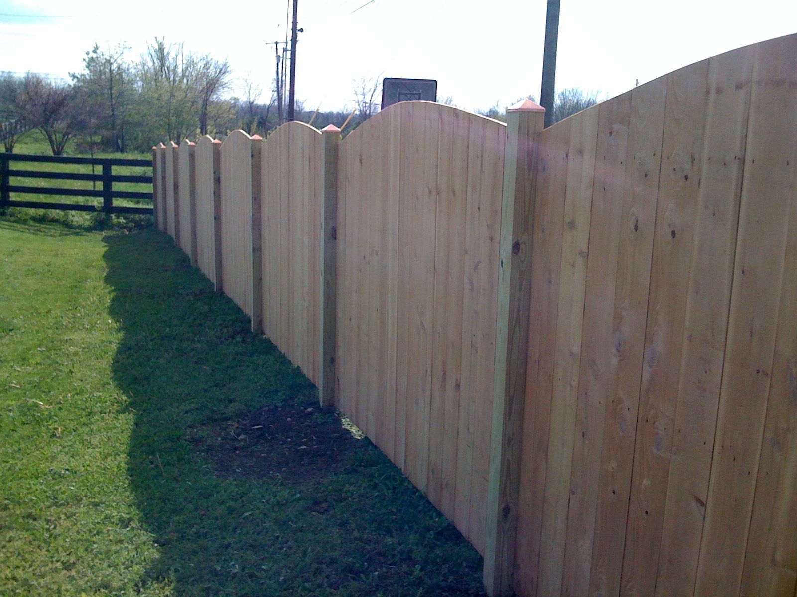 A wooden fence surrounds a lush green field.