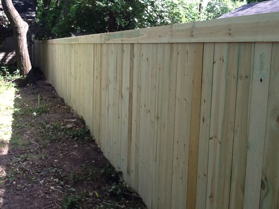 A wooden fence is surrounded by grass and trees.