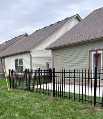 There is a black fence in front of a house.