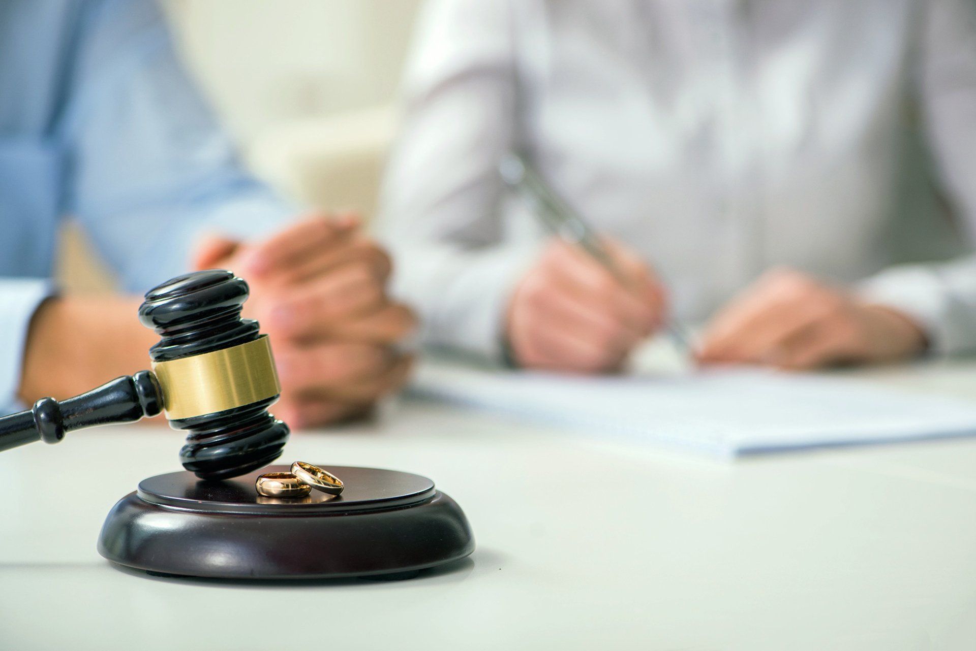 A judge 's gavel with a pair of wedding rings on it.