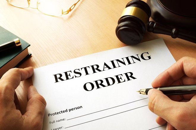 A person is signing a restraining order with a pen