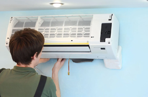 A man is installing an air conditioner on a wall.