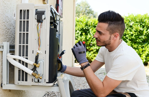 A man is working on an air conditioner outside of a building.