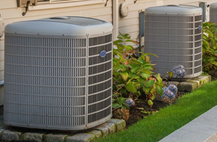 Two air conditioners are sitting on the side of a house.