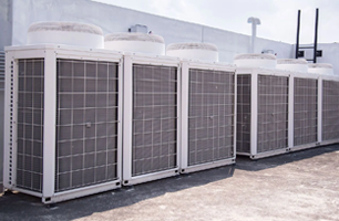 A row of air conditioners are sitting on top of a building.