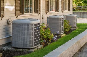 Three air conditioners are sitting on the side of a house.