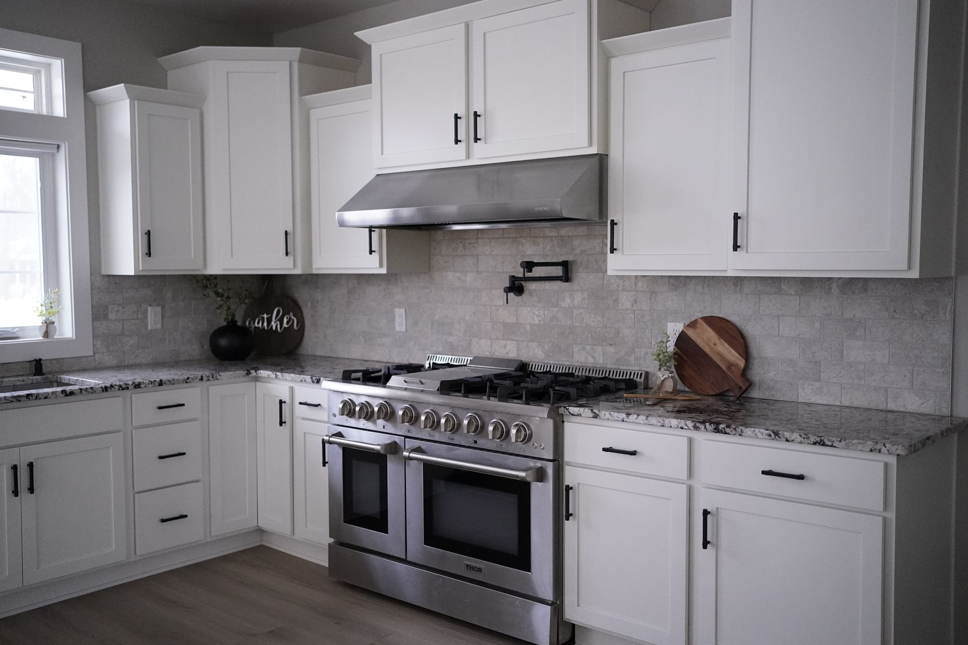 White kitchen with stainless steel appliances, cabinets, and gray countertops.