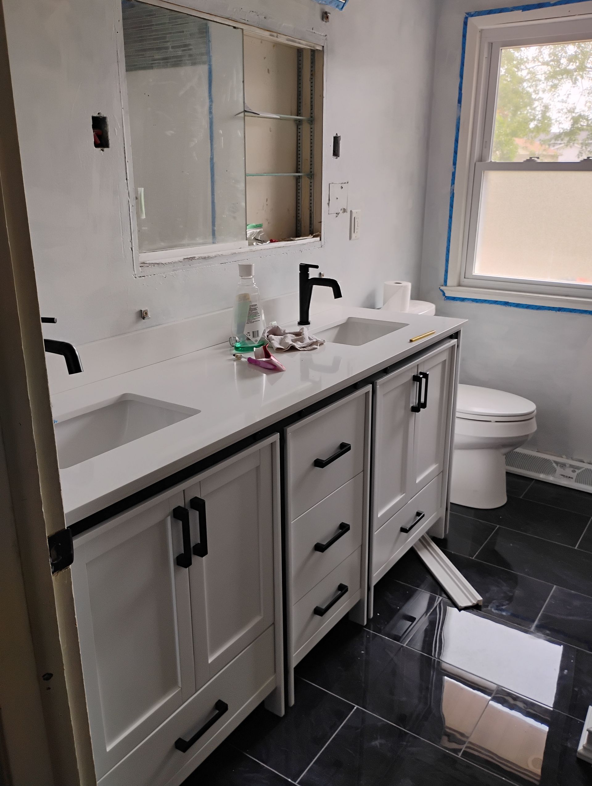 Bathroom renovation with white vanity, black hardware, dual sinks, and dark tile floor