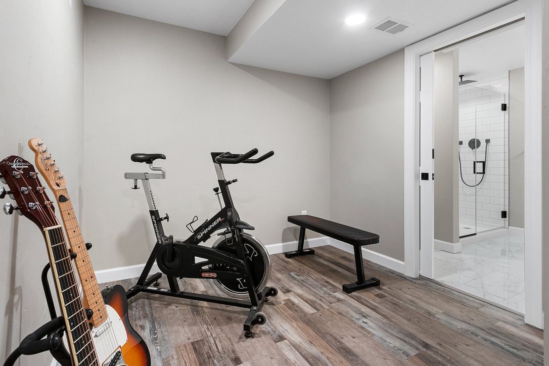 There is a spinning bike and a guitar in the room.