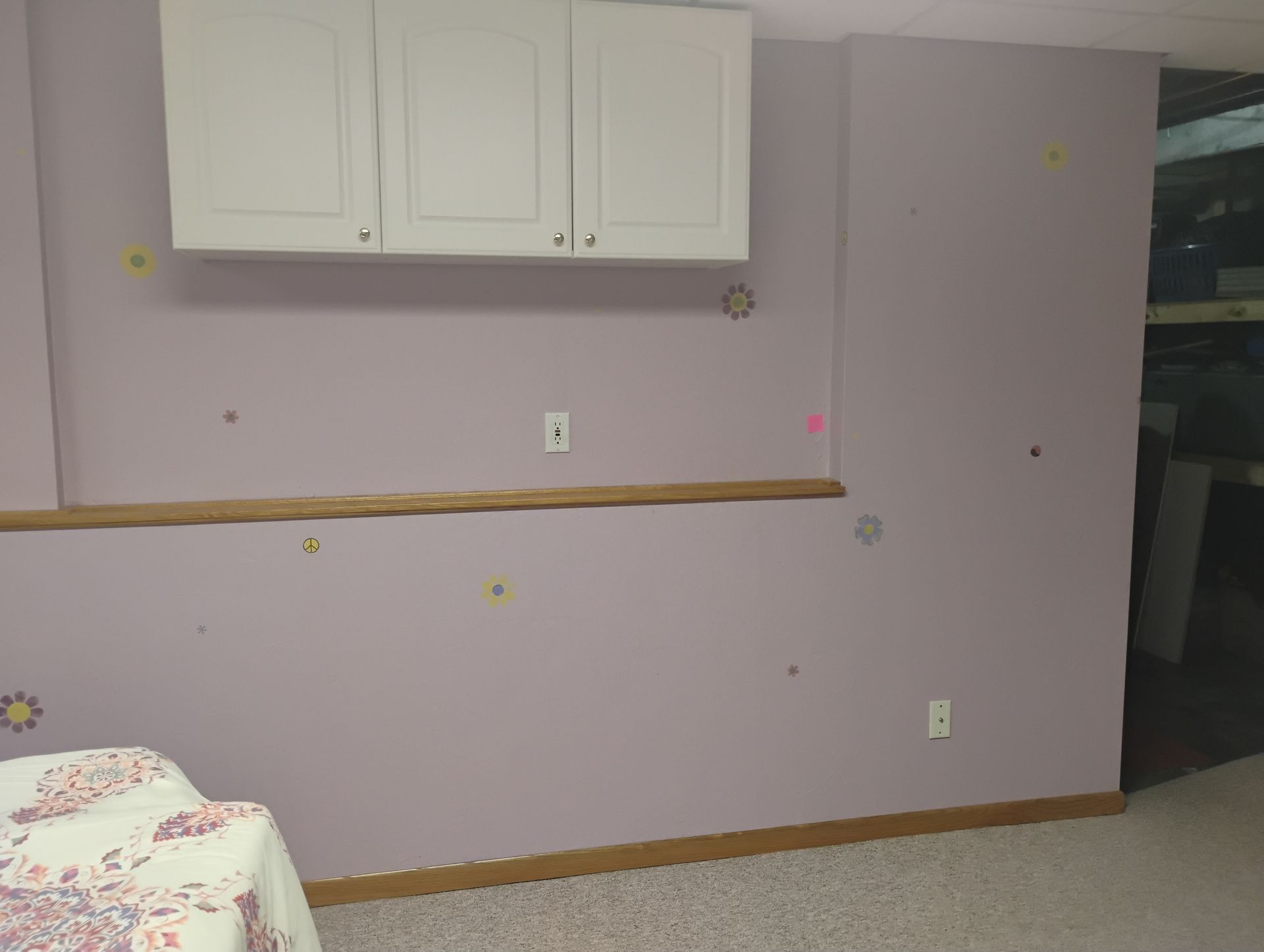 A room with white cabinets, a bed, and various circular stickers on the wall
