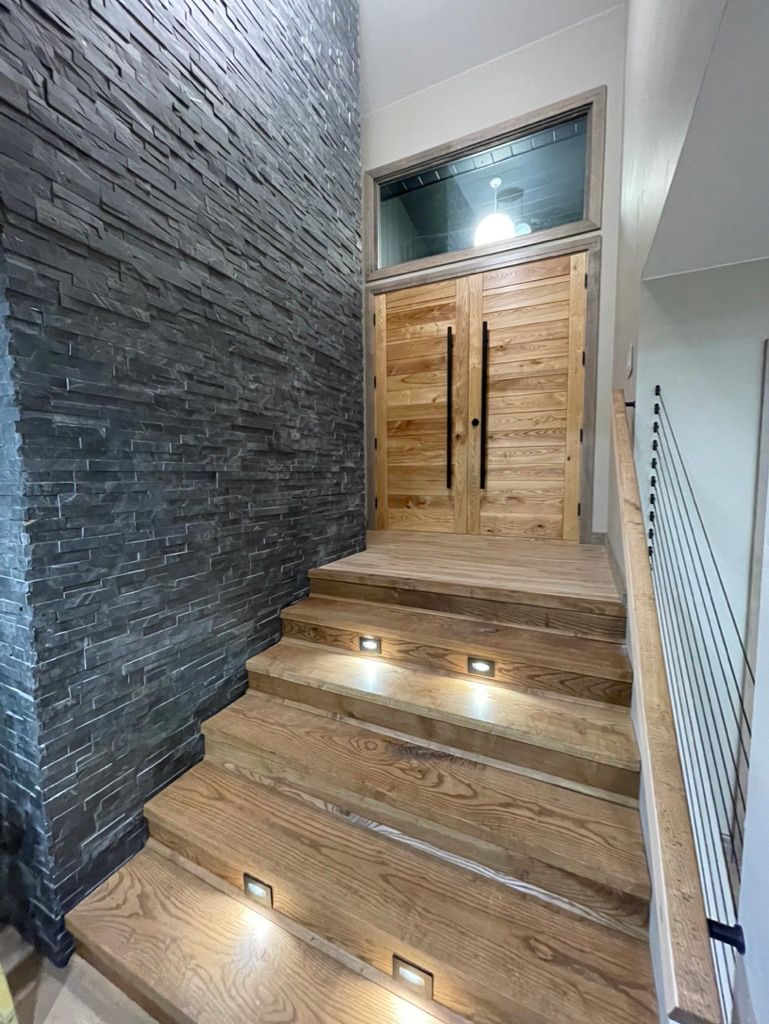 A set of wooden stairs leading up to a door in a house.