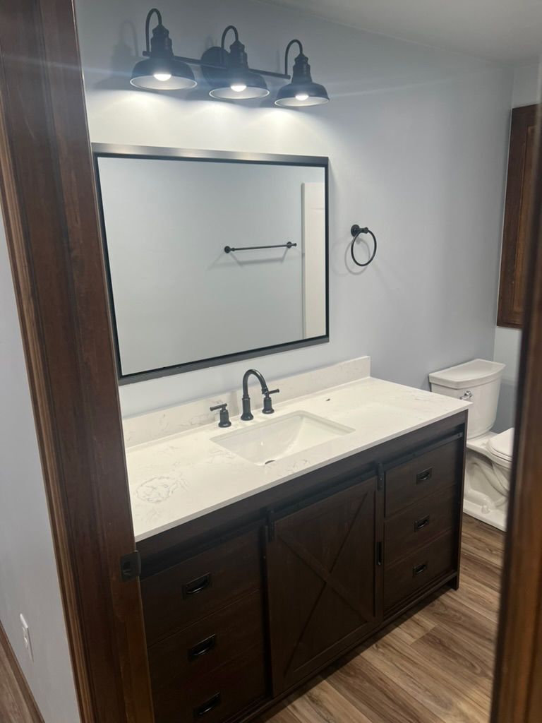 A bathroom with a sink , toilet and mirror.
