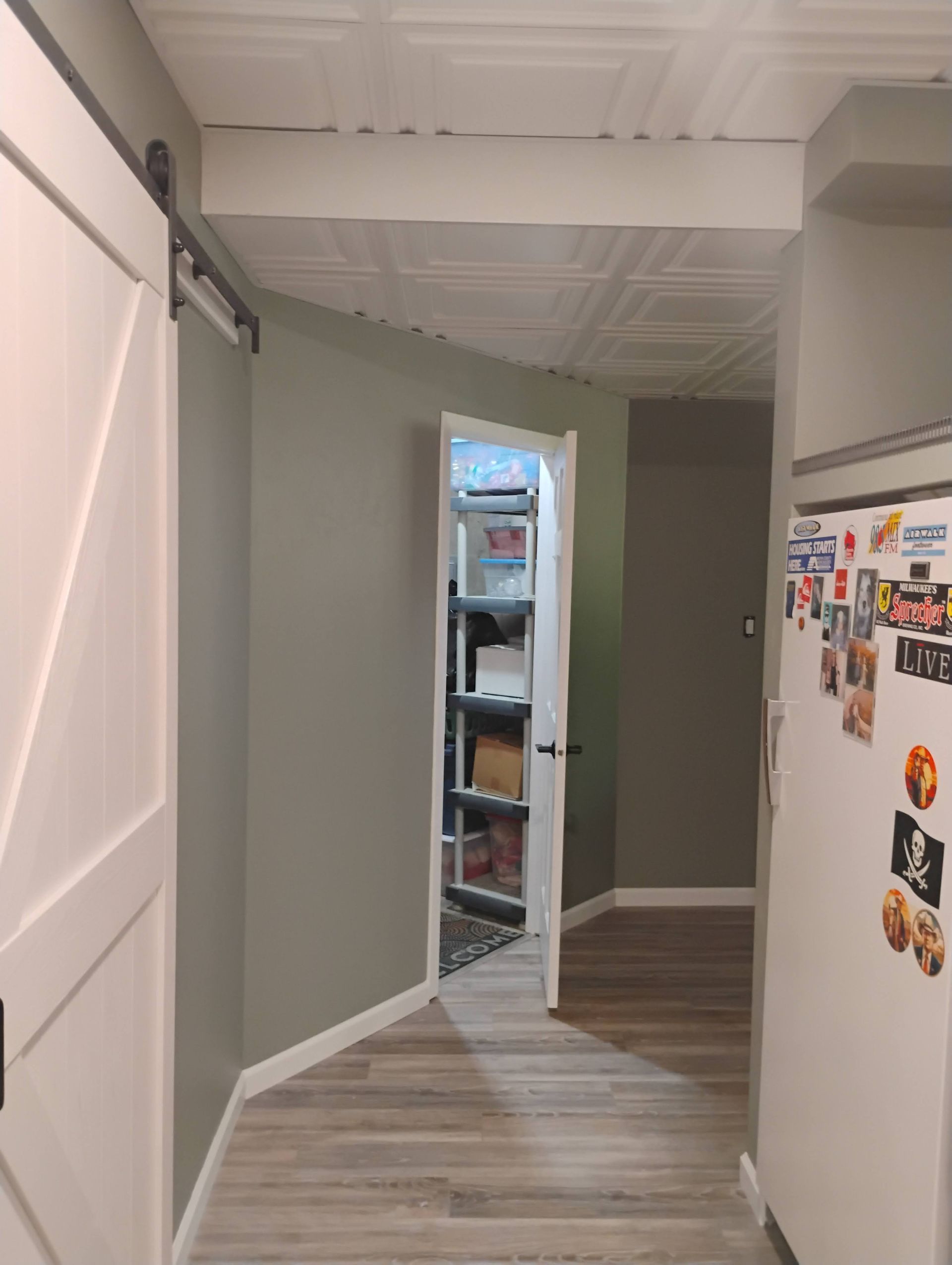Hallway with sliding barn door, pantry door, and refrigerator with magnets