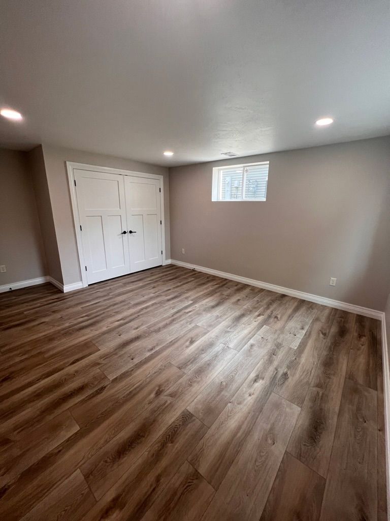 A large empty room with hardwood floors and a window.