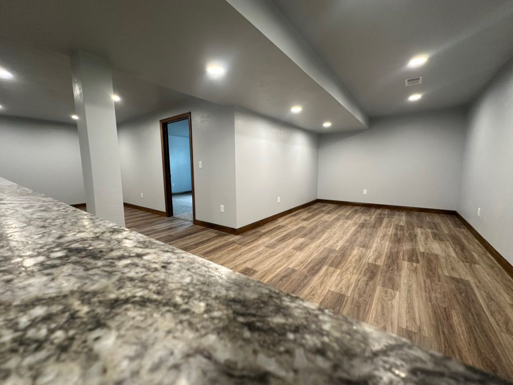 A large empty room with hardwood floors and white walls.