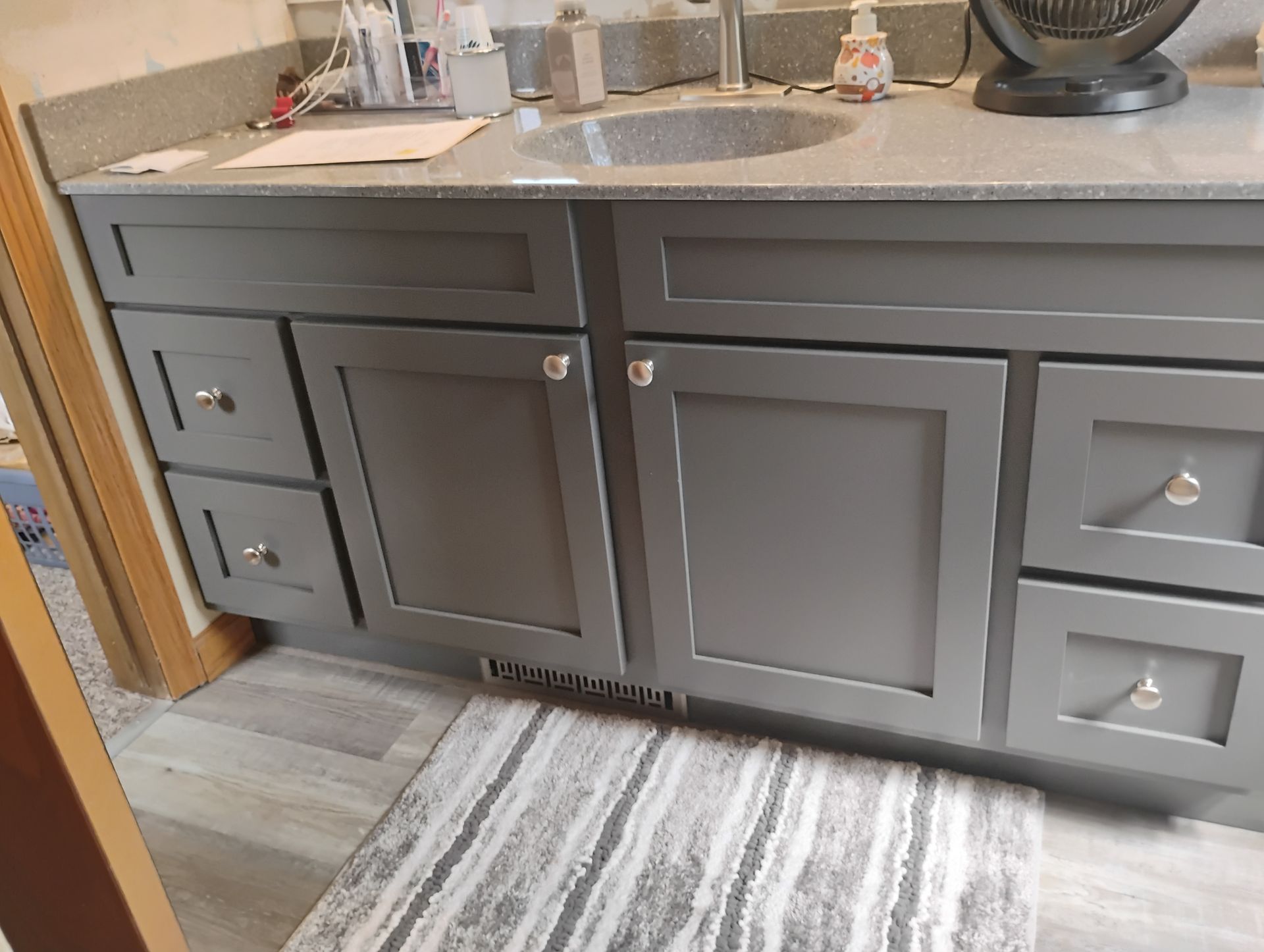 Gray bathroom vanity with drawers, doors, and a countertop with a sink