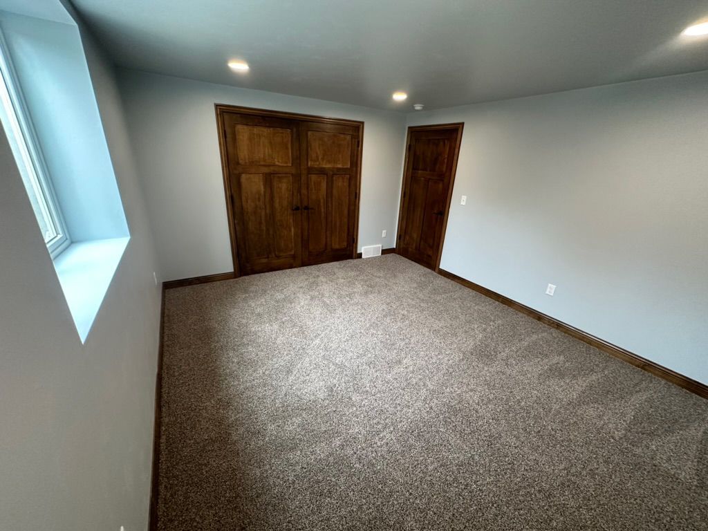 An empty room with a carpeted floor and a window.