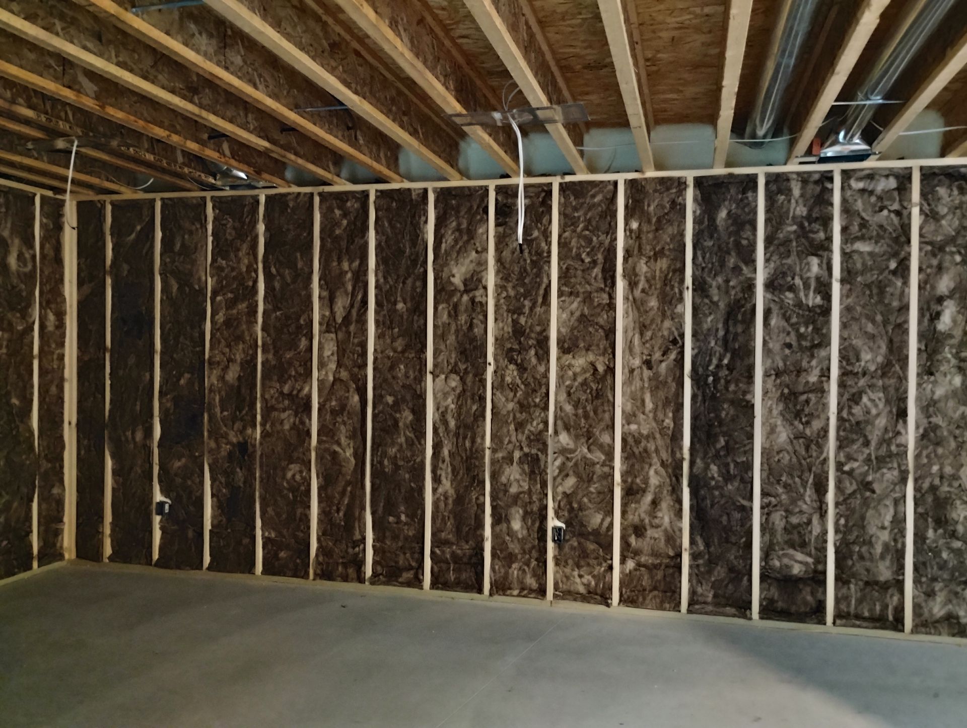 Interior view of a framed wall with insulation installed between wooden studs