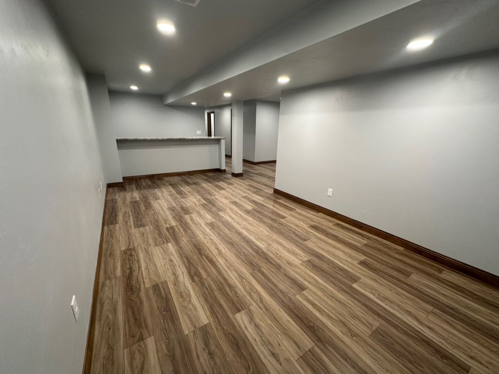 A large empty room with wooden floors and gray walls.