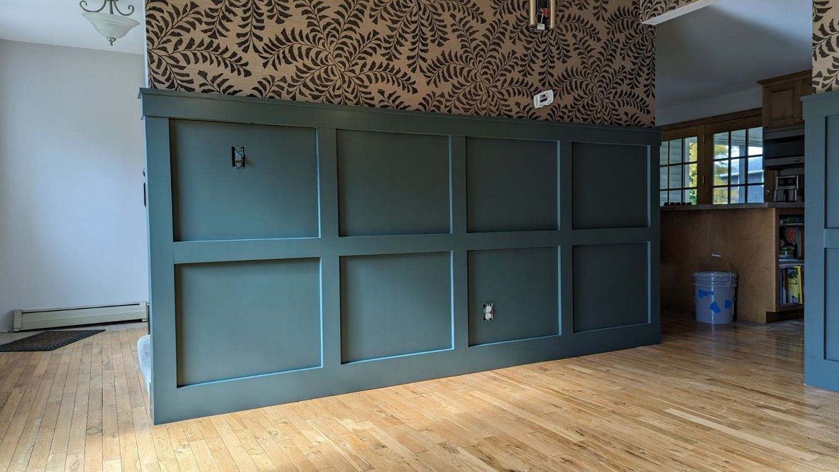 An empty room with a green wall and a wooden floor.