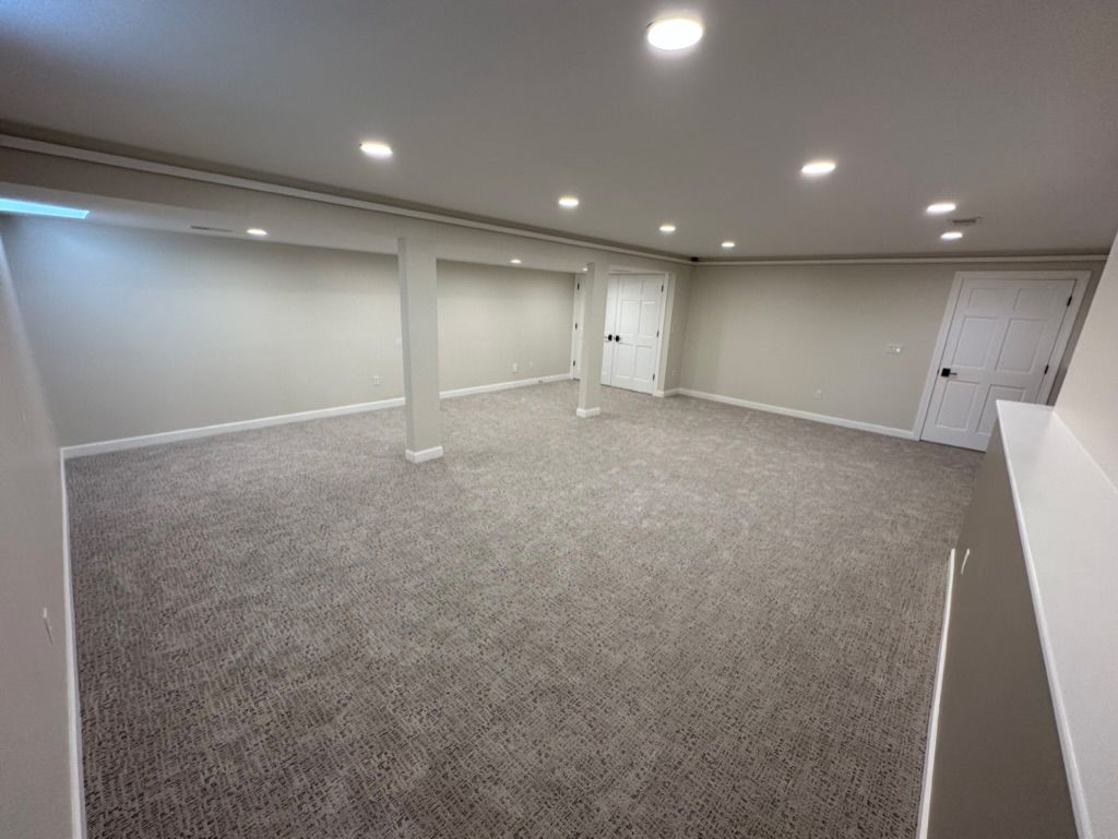 An empty basement with a carpeted floor and a ceiling.