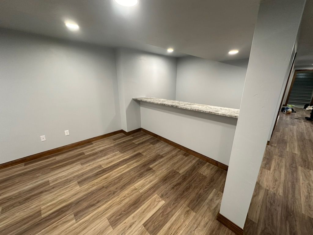 An empty room with hardwood floors and a counter.