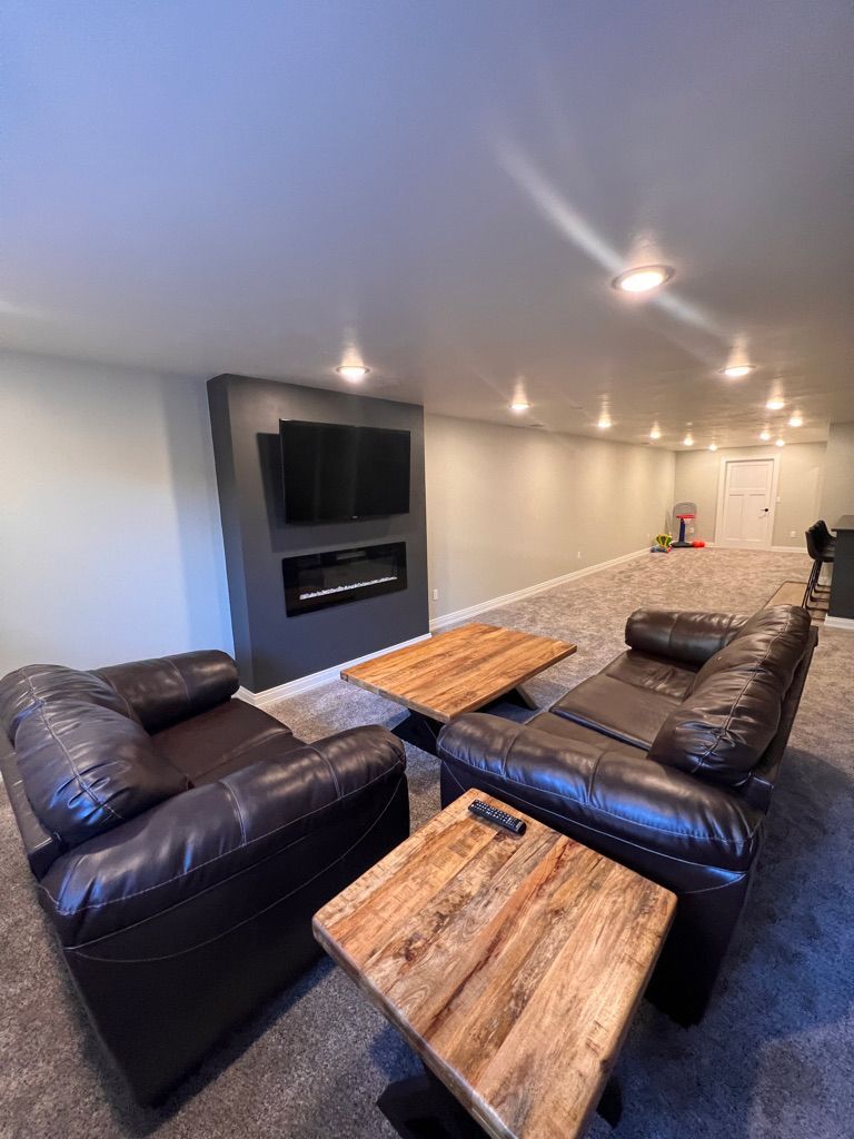 A living room with a couch , two chairs , a coffee table and a flat screen tv.