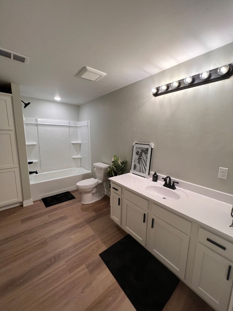 A bathroom with a sink , toilet , bathtub and mirror.