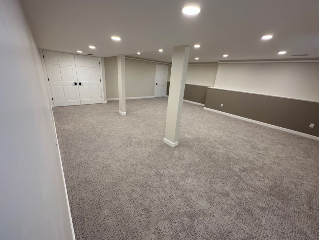An empty basement with a gray carpet and white walls