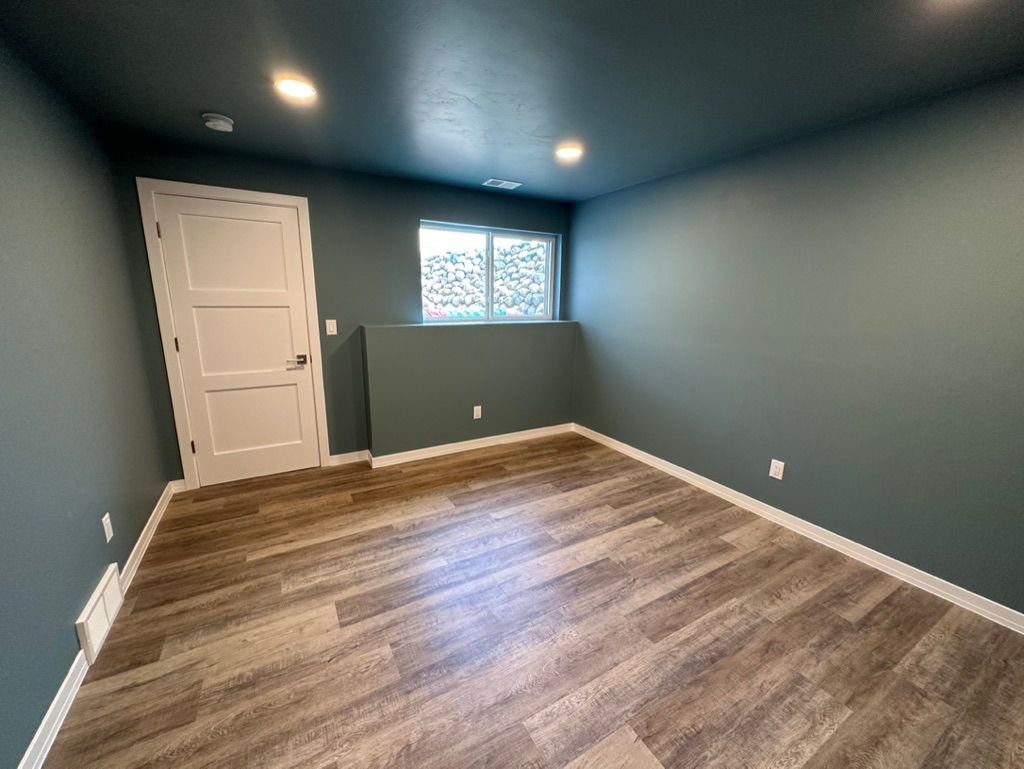 An empty room with a wooden floor and blue walls.