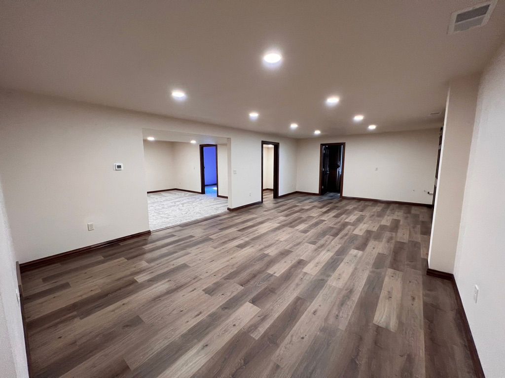 A large empty room with hardwood floors and white walls.