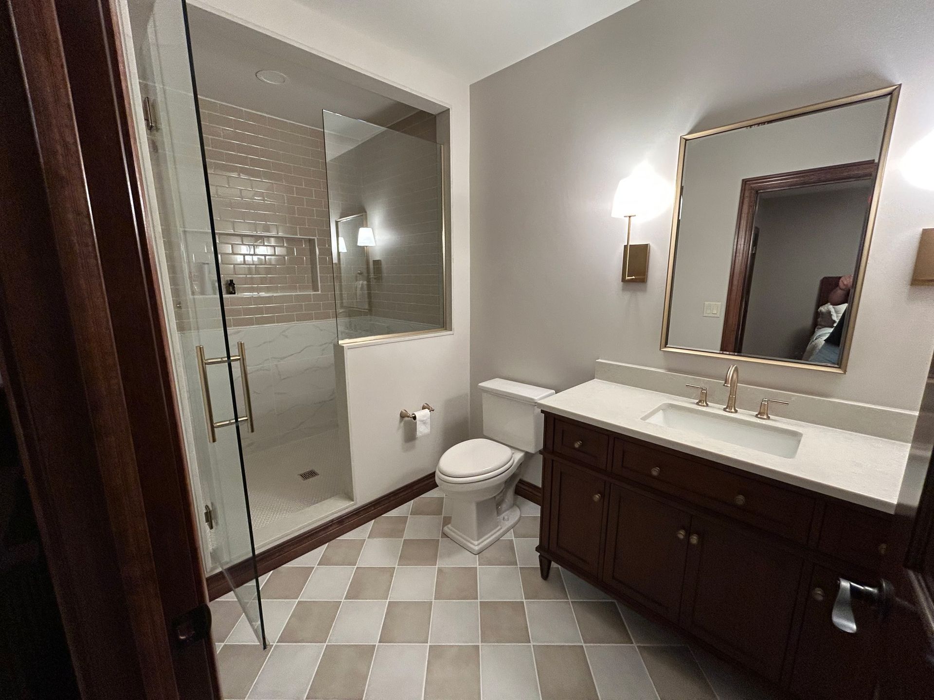 A bathroom with a toilet , sink , mirror and walk in shower.