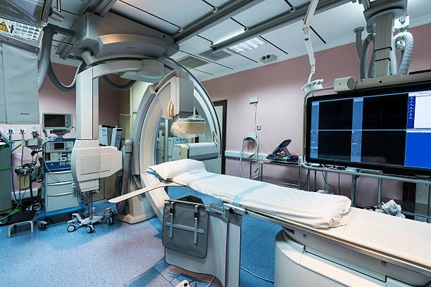 An empty operating room with a bed and a monitor.