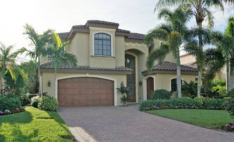 A large house with a garage and palm trees in front of it