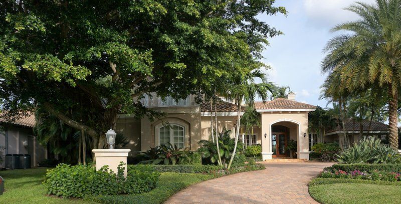 A large house with a brick driveway and palm trees in front of it