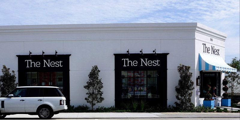 A white suv is parked in front of a store called the nest