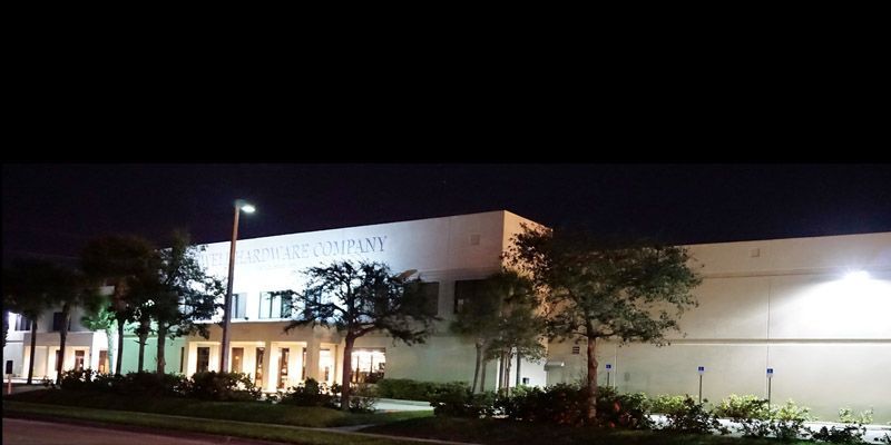 A large building is lit up at night with trees in front of it.