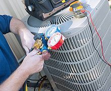 AC technician using testing equipment on outside unit