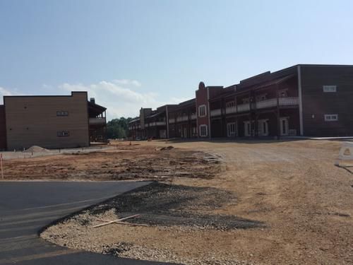 A row of buildings are being built next to a gravel road.